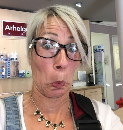 Frau probiert Brille beim Optiker aus und zieht dabei Grimassen